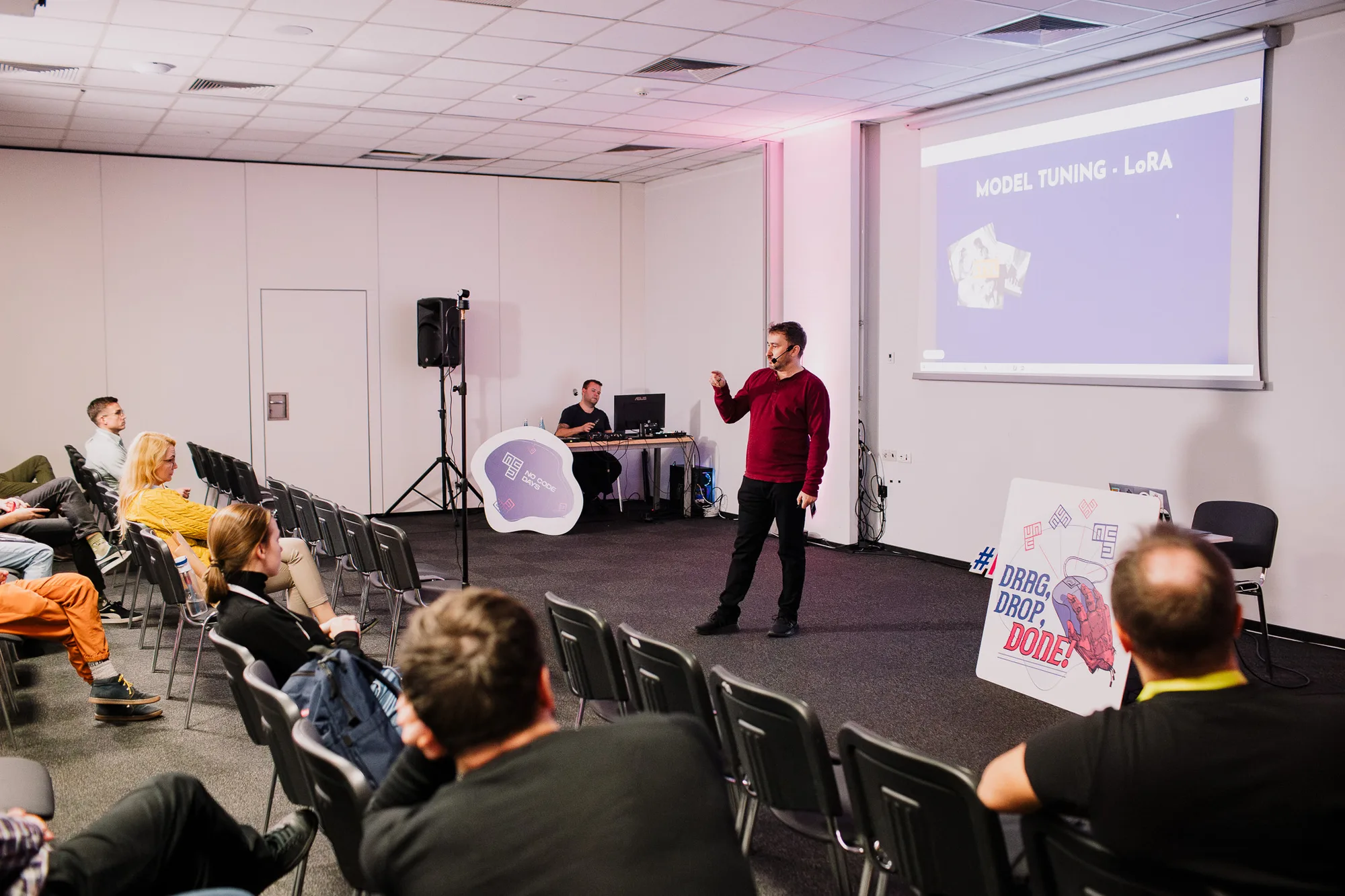 Krystian Wydro przemawia do publiczności na tle ekranu z prezentacją podczas No Code Days 2024 w Warszawie